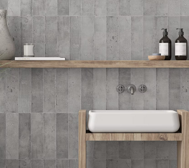 Bathroom with gray tiled walls, wooden shelf, and white sink.